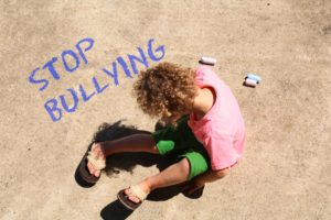 Niño sentado en el suelo junto al mensaje escrito "Stop Bullying"