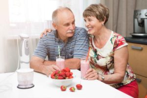 Pareja de ancianos tomando un batido sonrientes