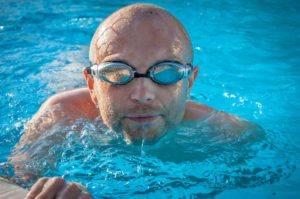 Chico con gafas nadando en piscina