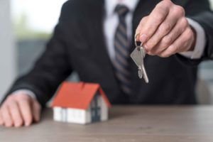 Chico trajeado con una casa detrás