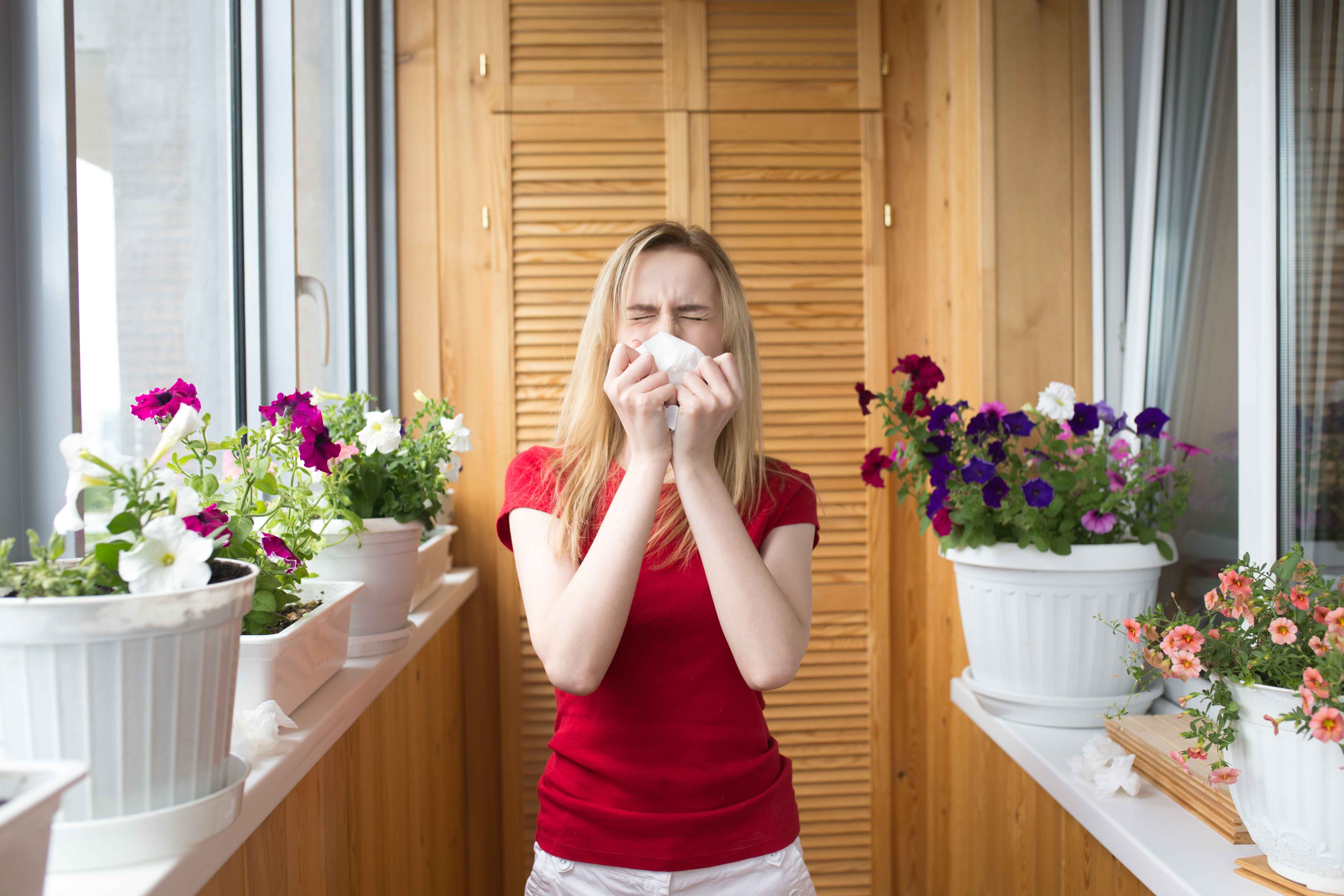Chica estornudando en un balcón con plantas