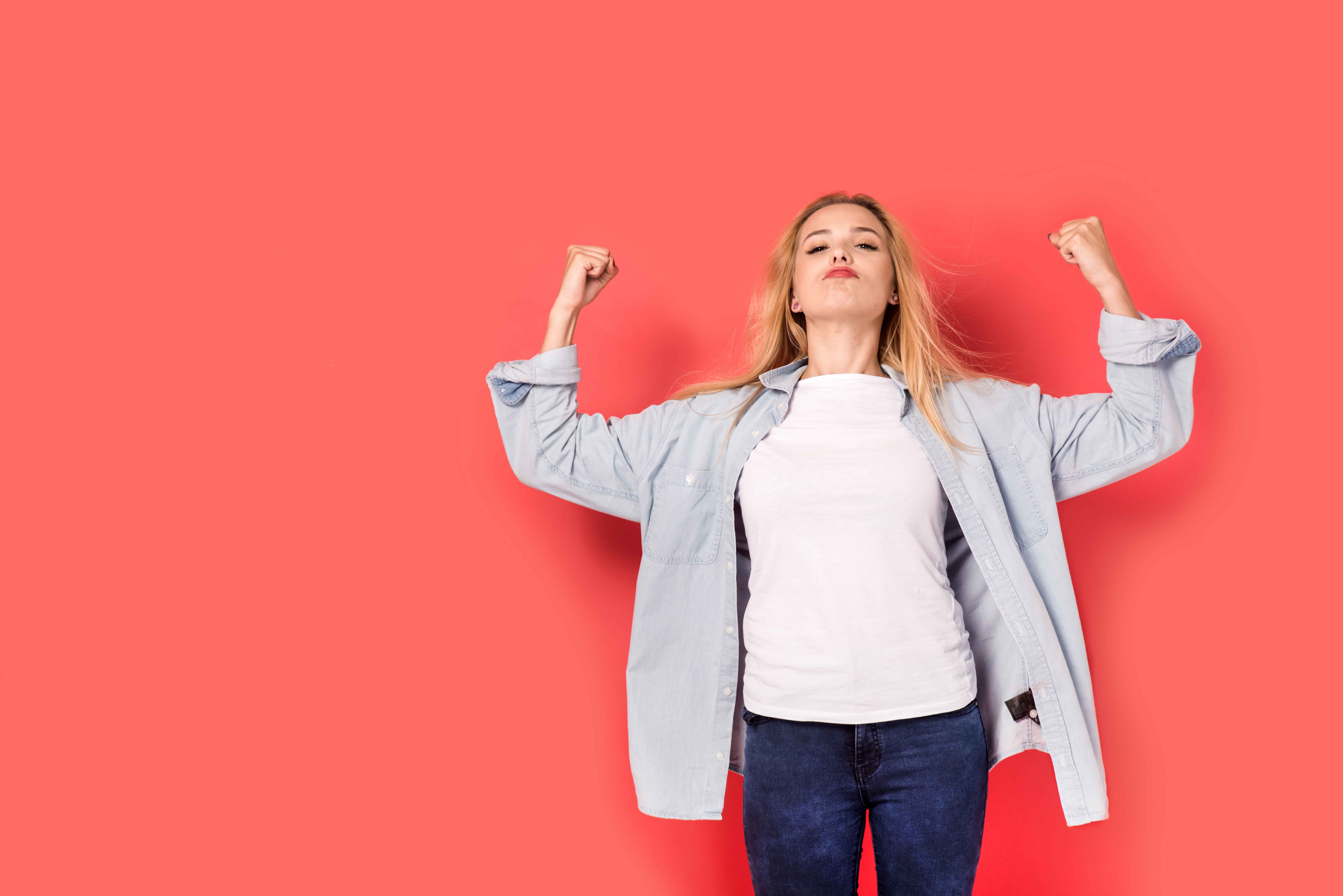 Chica con pose de fuerza sobre fondo rojo