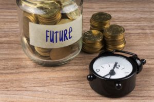 Reloj al lado de bote con monedas