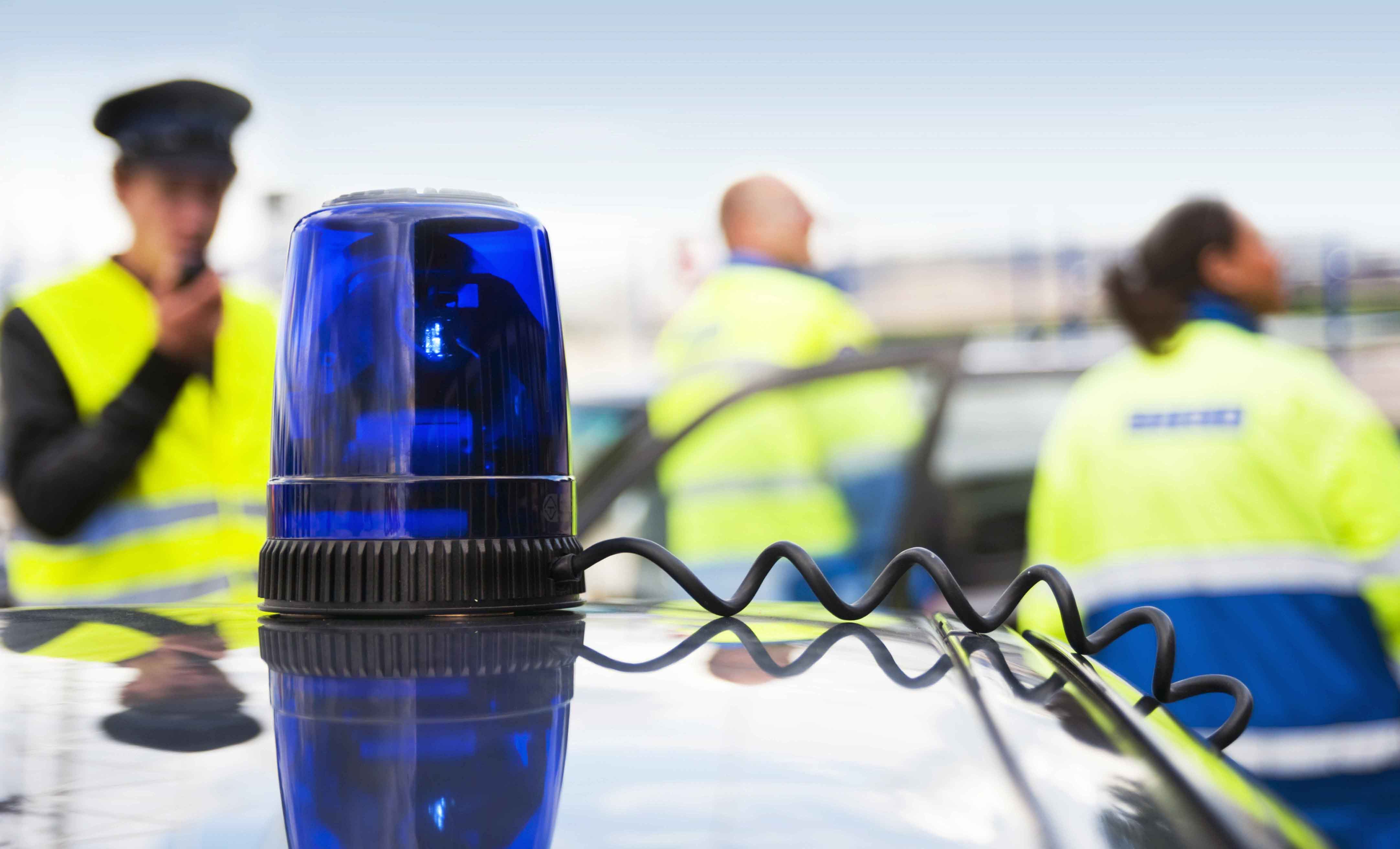 Policía de fondo tras sirena de coche