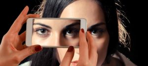 Imagen simbólica de chica a la que le están tomando una foto de la mirada con un móvil