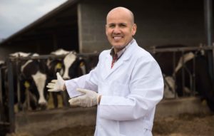 Veterinario delante de establo de vacas