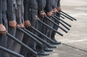 Fila de policías con bastón extensible en la mano