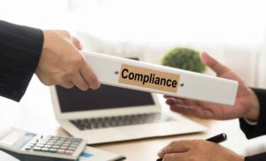 Mano entregándole a otra en un despacho un testigo que pone "compliance"