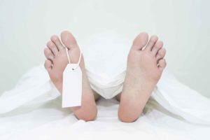 Piés de un cadáver tapado con sábana