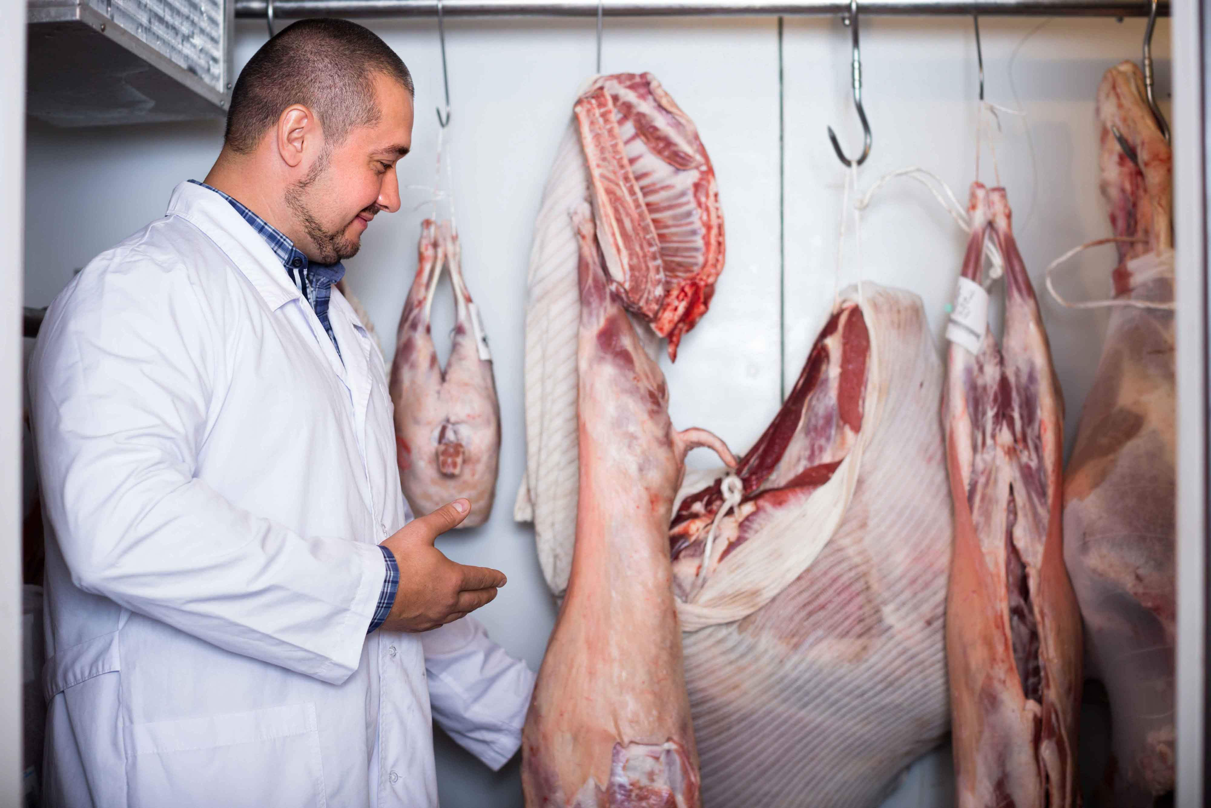 Carnicero junto a piezas de carne