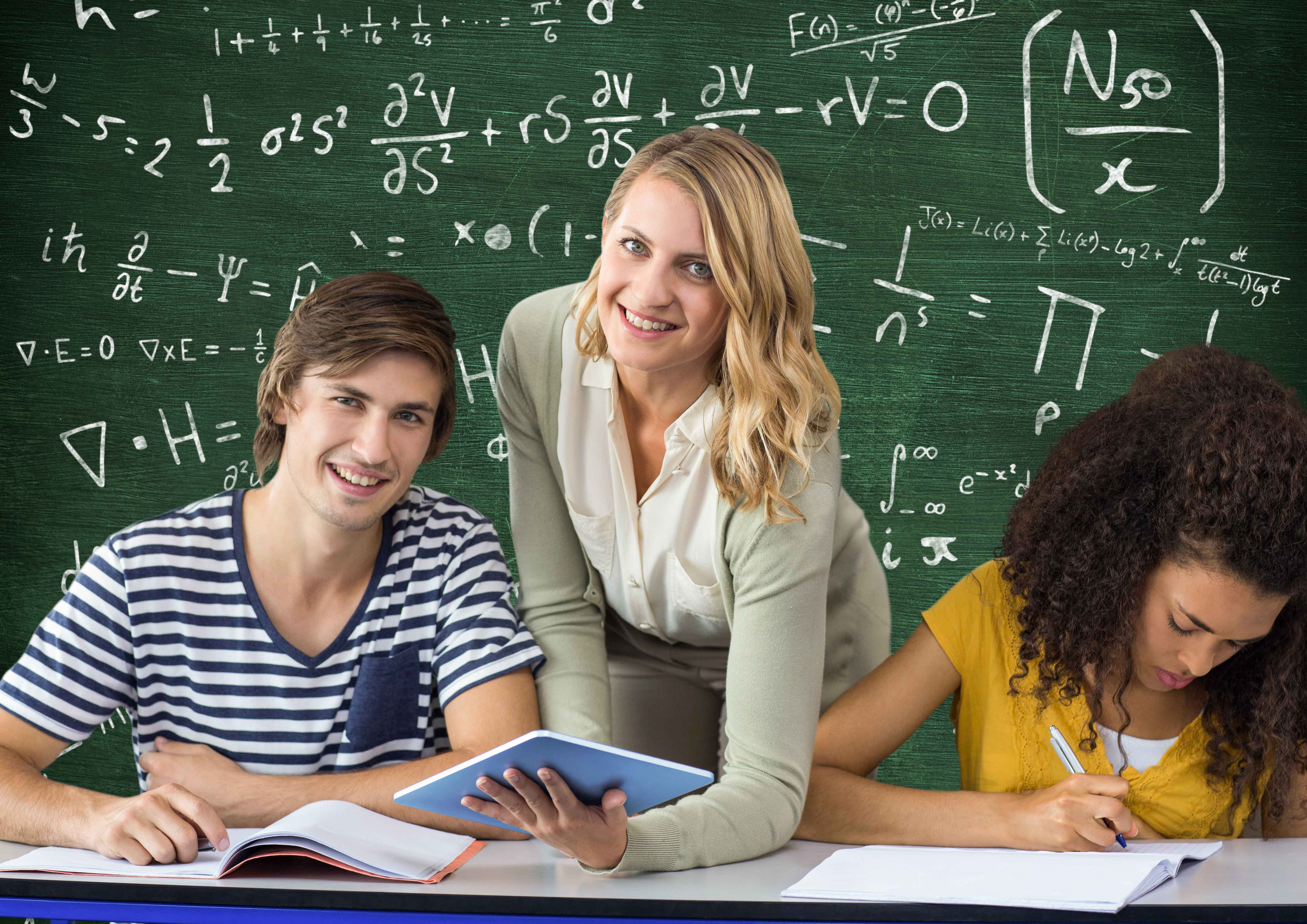 Profesora explicando a niño y niña matemáticas con pizarra atrás