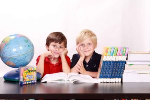 Dos niños sonrientes entre elementos escolares