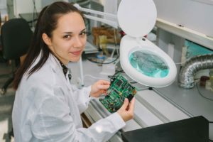chica trabajando sobre placa electrónica