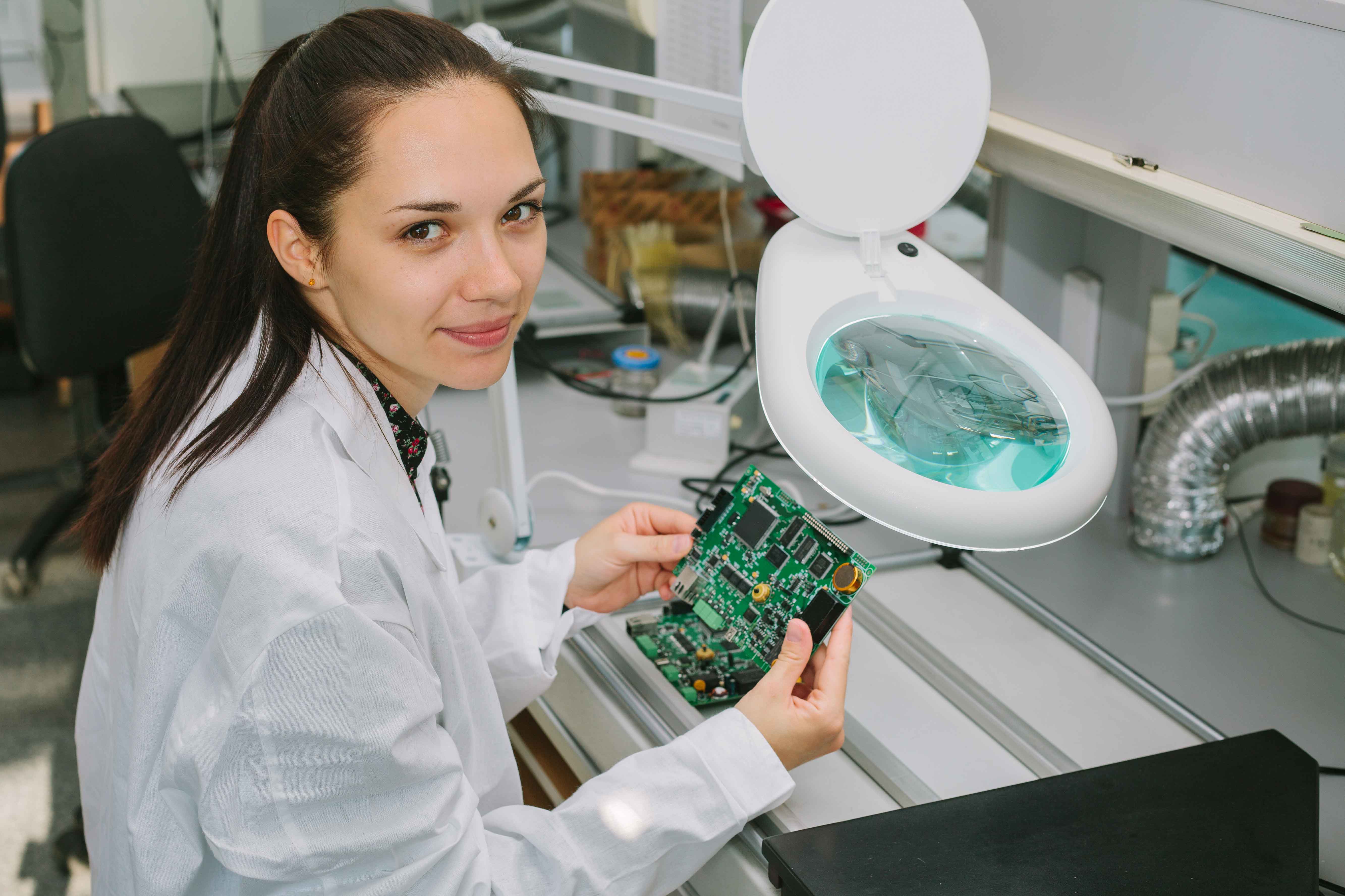 chica trabajando sobre placa electrónica