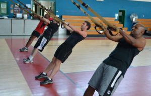 Tres personas entrenando con cintas TRX