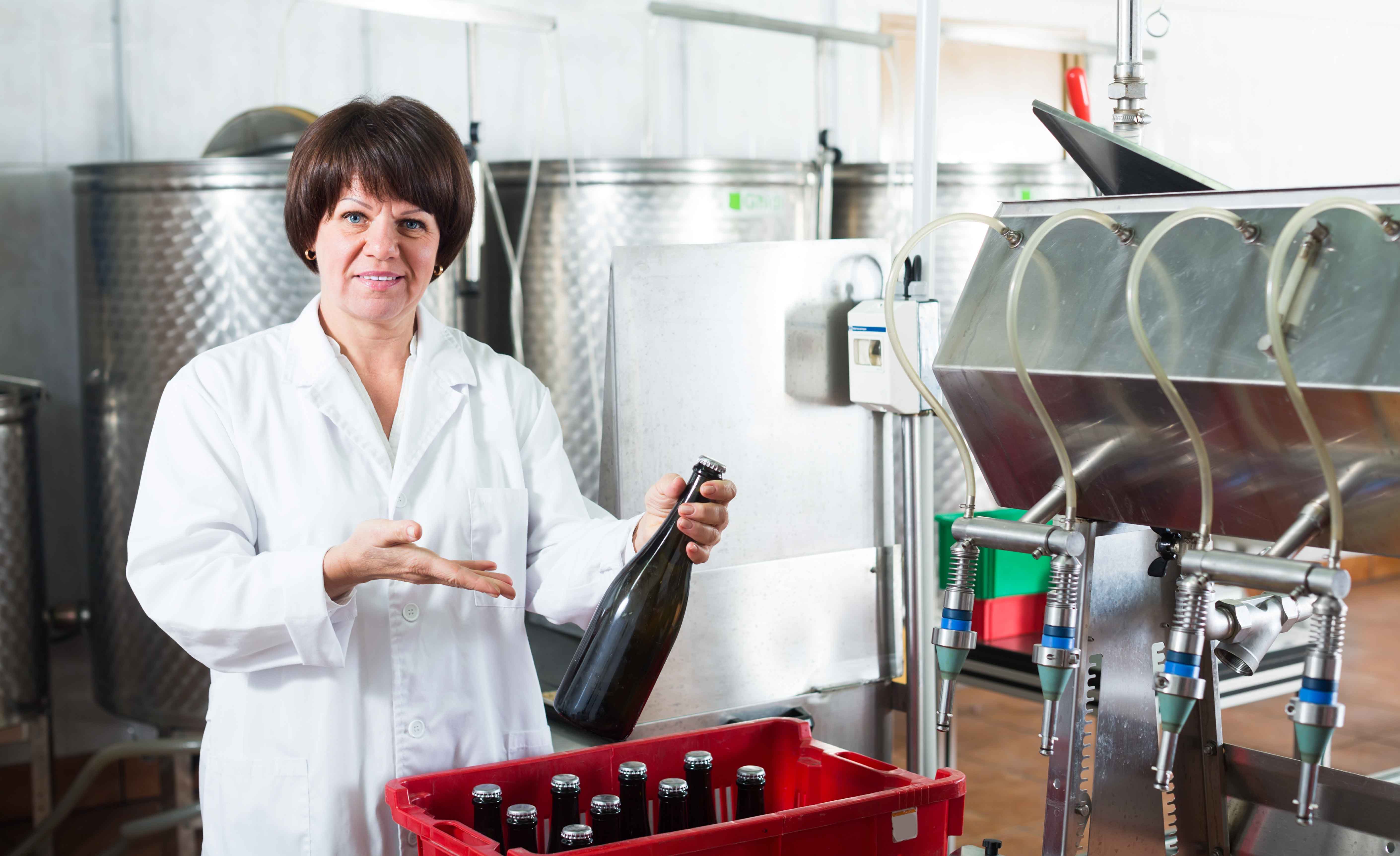 Mujer posando con bebidas en una fábrica