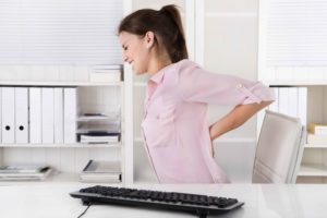 Chica en silla de oficina con dolor de espalda