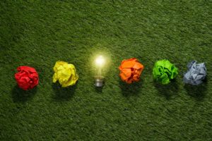Foto de bombilla y bolas de papel de colores sobre un césped