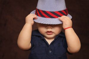 Niño con sombrero tapándose la cara