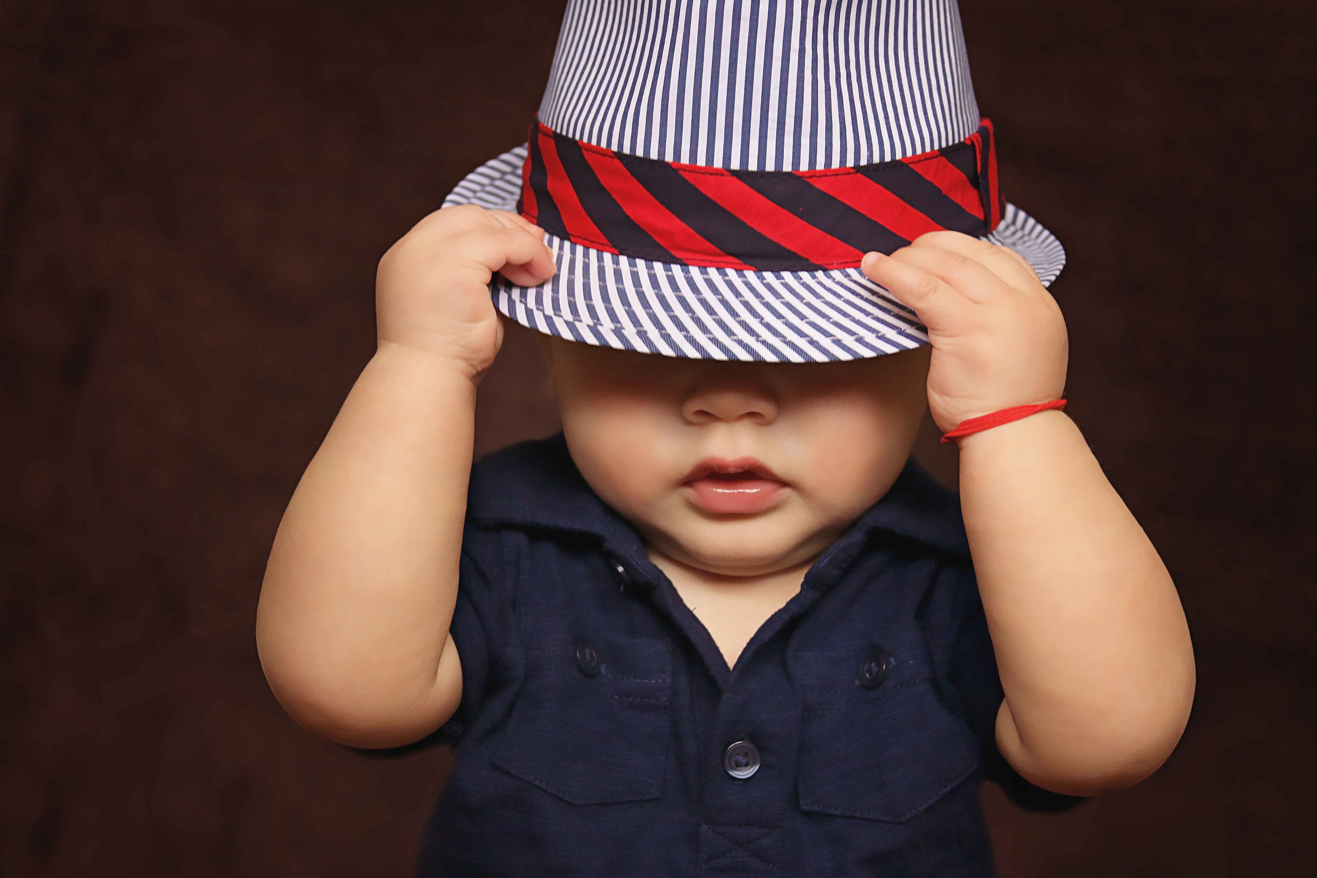 Niño con sombrero tapándose la cara