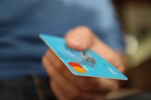 Persona con tarjeta bancaria en la mano