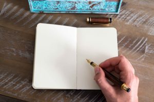 Mano con pluma estilográfica en mano a punto de escribir sobre libreta