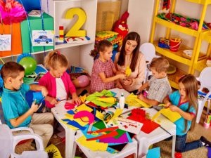 Profesora haciendo manualidades con niños en gardería