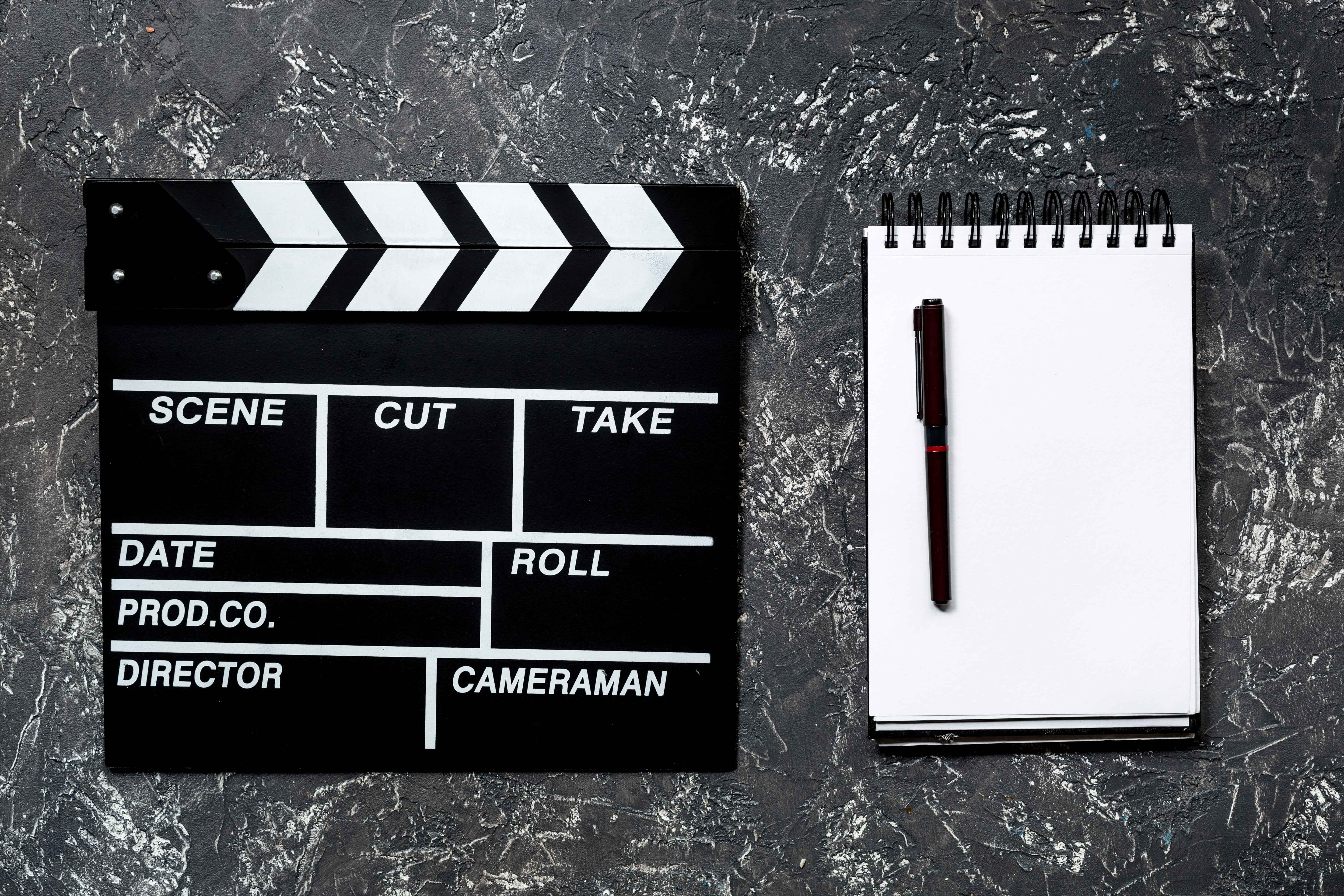 Claqueta de cine y libreta en blanco al lado