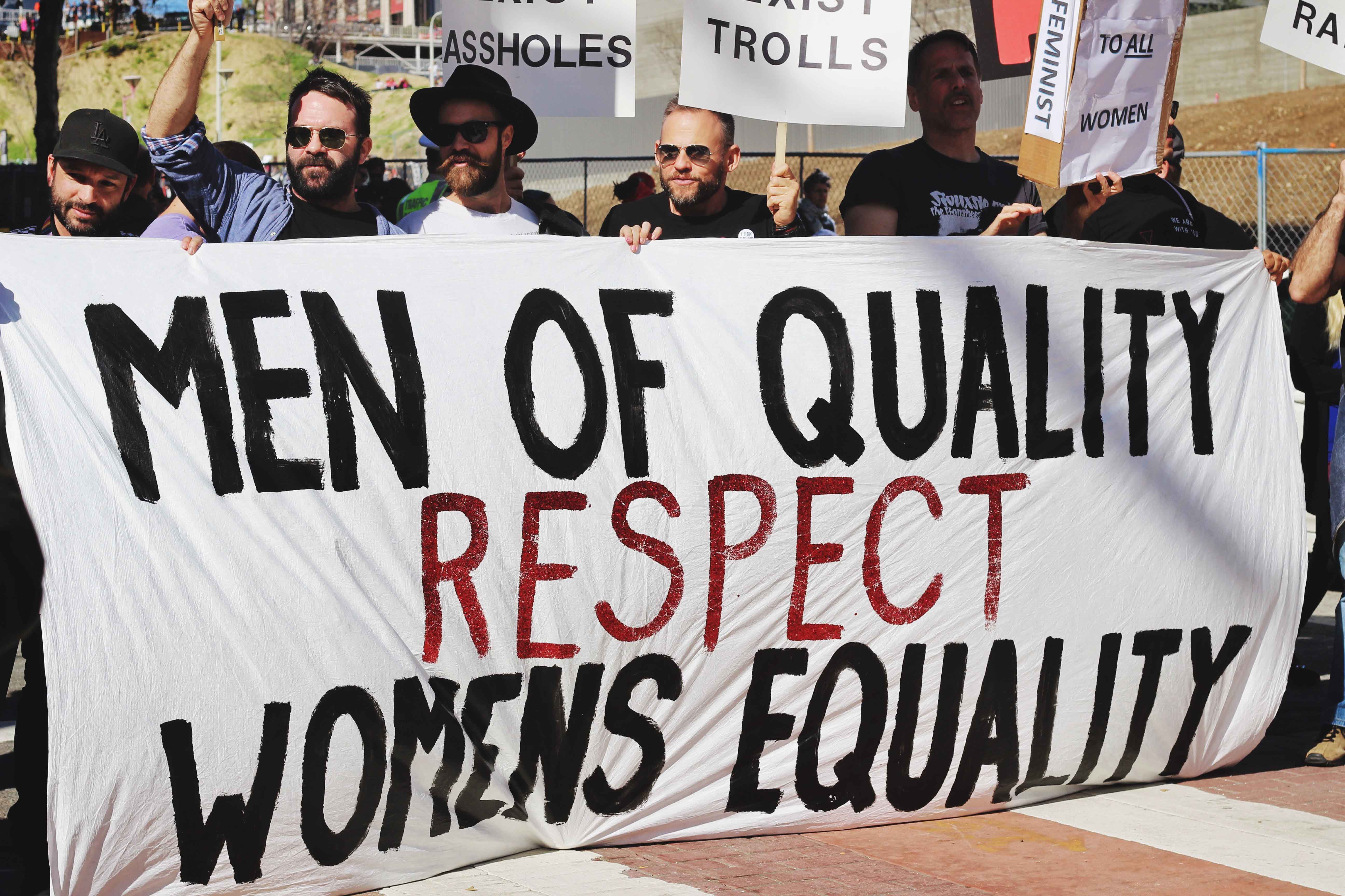 Manifestación de hombres portando pancarta con el texto "Los hombres de calidad respetan a las mujeres en igualdad"