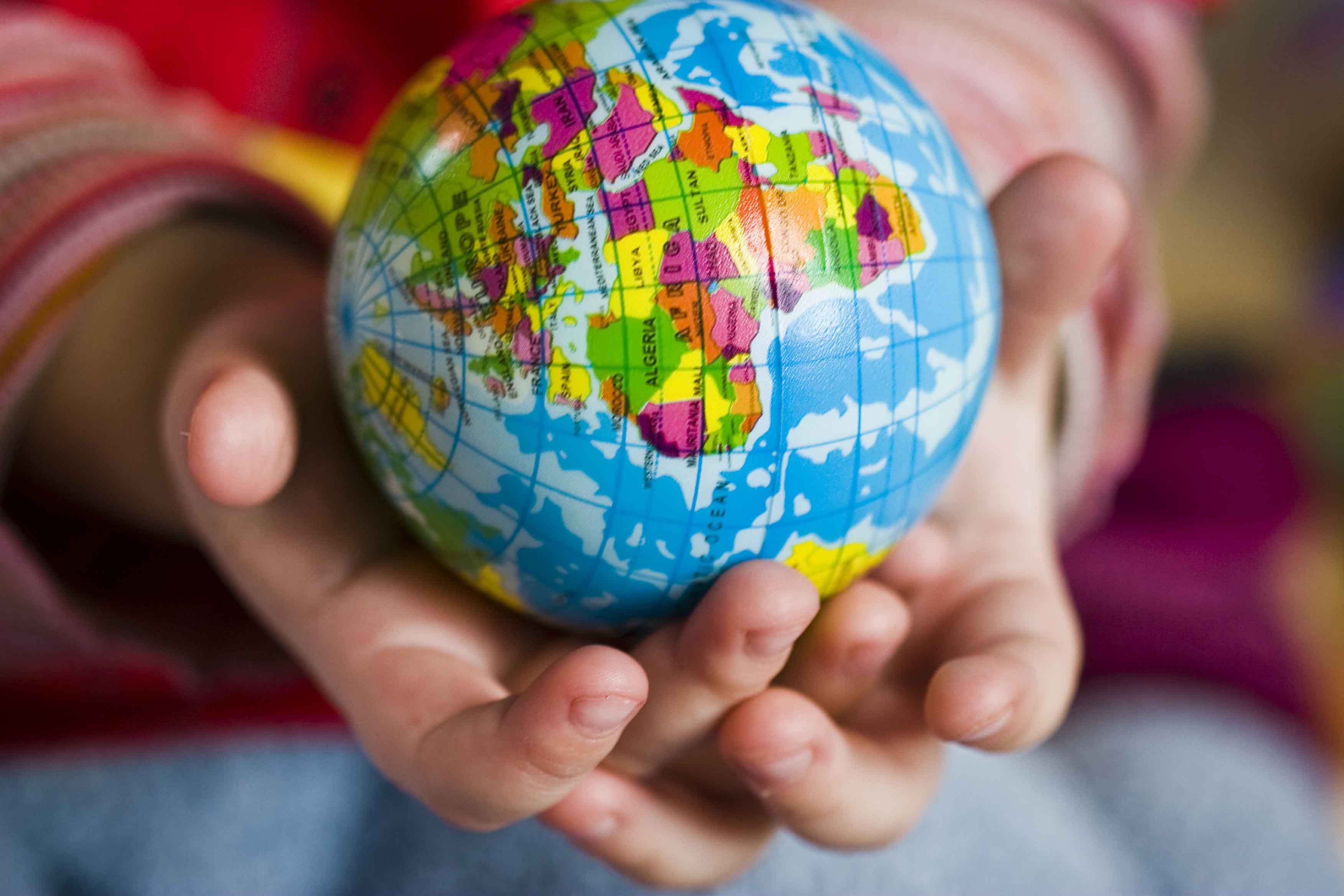 Manos de niño con bola del mundo en la mano