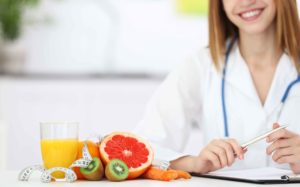 Doctora con plato de frutas y verduras delante