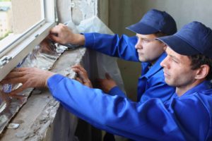 Dos trabajadores colocando aislamiento térmico a ventana