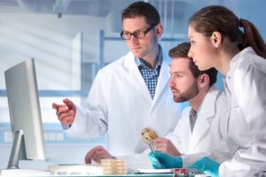 Tres personas con bata médica mirando pantalla de ordenador