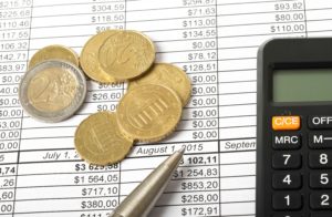 Monedas y calculadora sobre hoja de cálculo