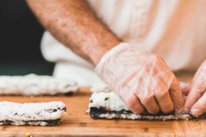 Manos de cocinero preparando sushi