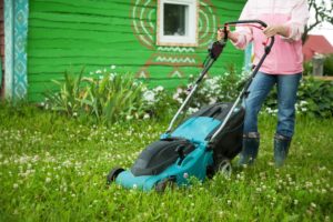 Mujer cortando el césped con cortacesped