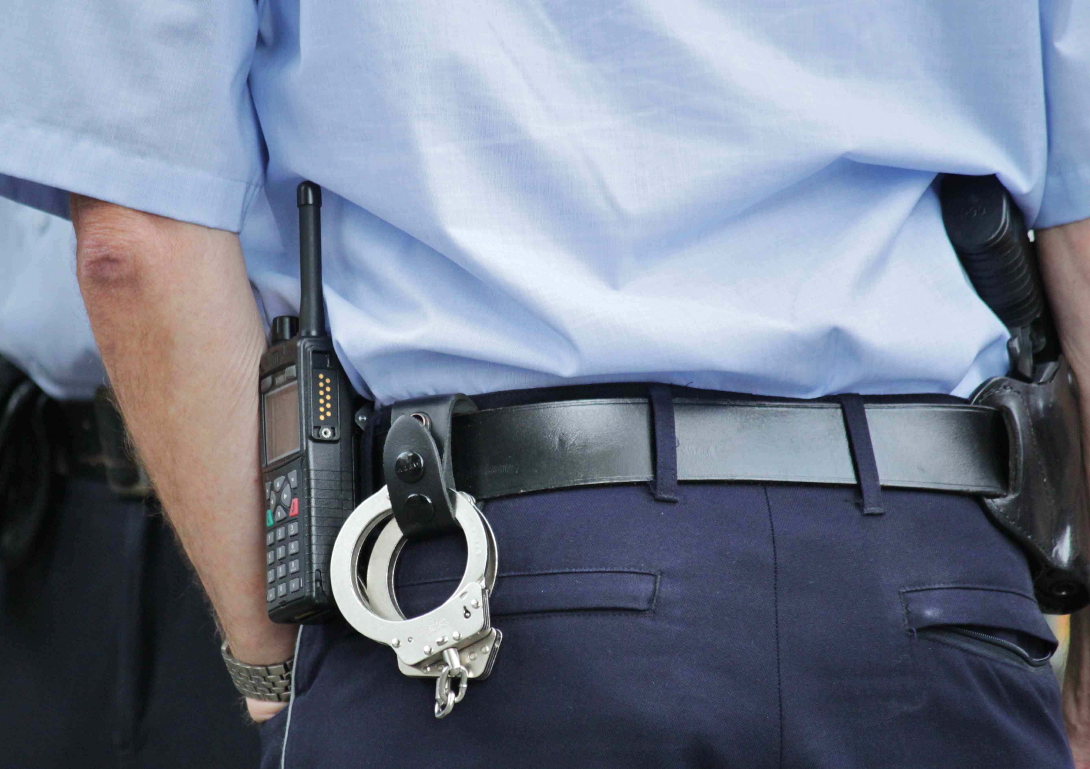 Esposas y radio de un guardia de seguridad de espaldas