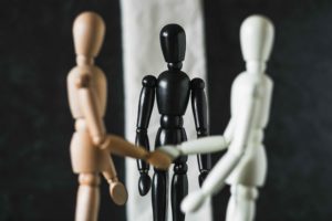 Figuras de madera de colores diferentes dándose la mano