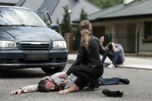 Chica atendiendo a víctima de accidente en el suelo con otra víctima de fondo