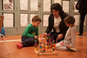 Maestra jugando con dos niños en el suelo de una ludoteca