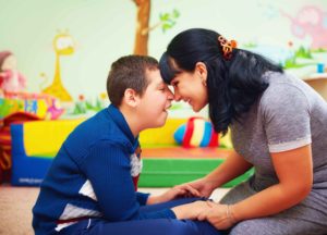 Chica jugando cariñosamente con niño con discapacidad psíquica