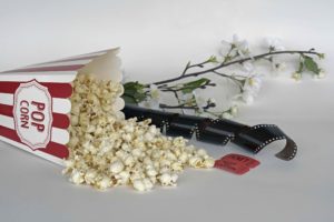 Paquete de palomitas caído con película cinematográfica al lado
