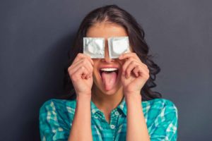 Imagen divertida de chica tapándose los ojos con dos preservativos