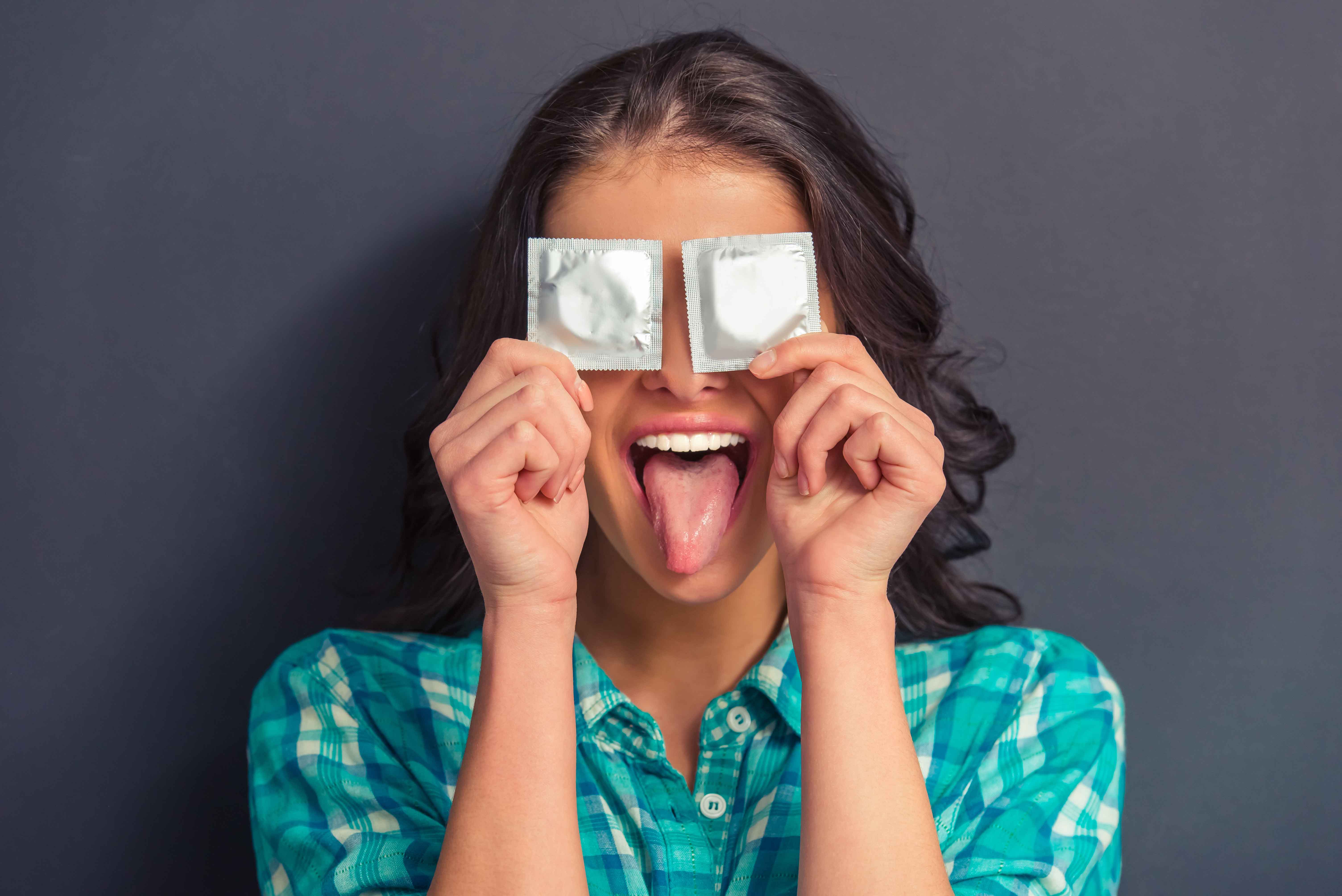 Imagen divertida de chica tapándose los ojos con dos preservativos