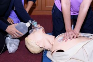Gente practicando reanimación cardiopulmonar con maniquí