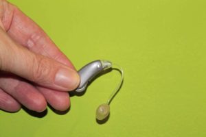 Prótesis auditiva sobre fondo verde