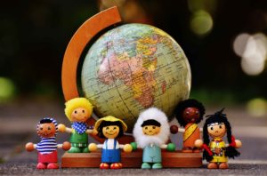 Figuras de gente de varias razas junto a bola del mundo