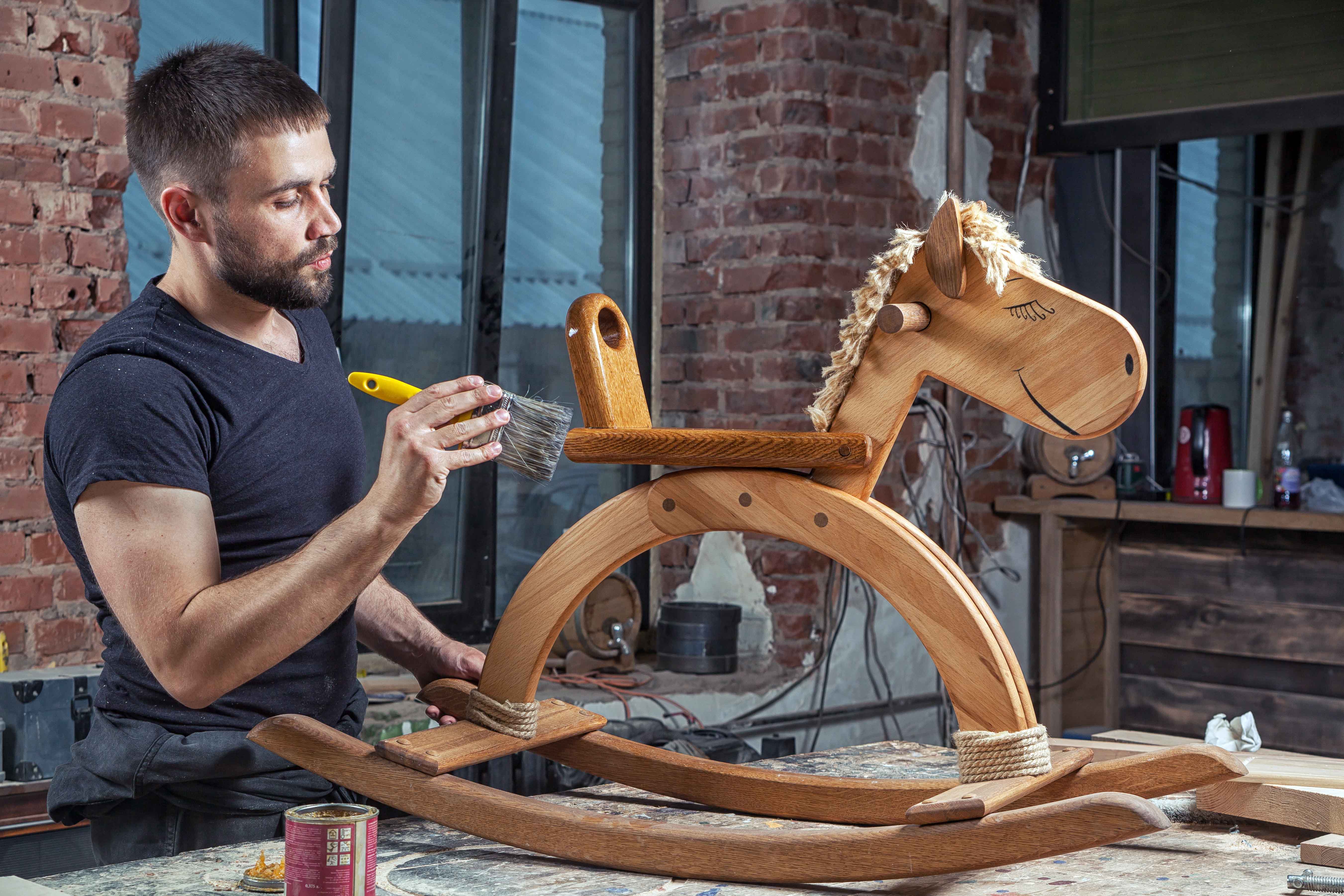 Chico trabajando reparando caballito de madera de juguete