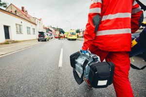 Técnico con maletín de material y ambulancias al fondo