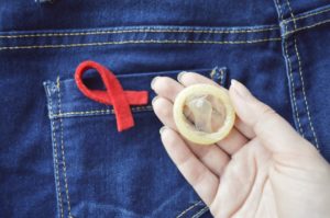 Lazo lucha contra el sida junto a bolsillo de pantalón vaquero y preservativo